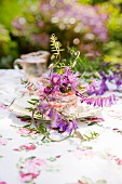 Wild flowers in old glass bowl on vintage plate as centrepiece on table in garden