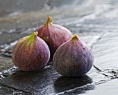 Three fresh figs on a slate surface