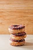 Three doughnuts with chocolate glaze and colourful sugar sprinkles