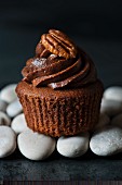 Single chocolate cupcake with pecan nut on pebbles