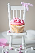 Single marshmallow cupcake with pink and white marshmallows on white dolls house chair with pink ribon