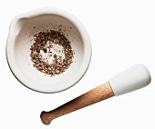 Spices in a mortar with a pestle against a white background