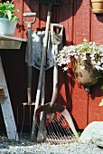 Vintage gardening equipment and plant pot hanging on rust red wooden wall