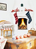 Pomegranates on wooden trunk and open fire in fireplace with Christmas decorations