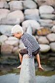 Boy sitting on log over stream