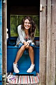 Smiling woman sitting inside outhouse