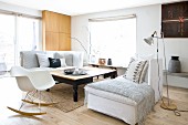 Two comfortable chaise sofas with scatter cushions and blankets and classic rocking chair around large wooden table in Scandinavian living room