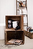 Vintage decor in old wooden crates in front of white-painted wood cladding and fashion magazines hung on rungs of ladder