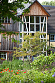 Bewirtschafteter Garten und ländliches Holzhaus mit mehrstöckigem Erker
