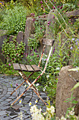 Rusty garden chair with wooden seat on grey paved terrace in garden