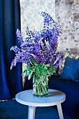 Blue and purple flowering lupins in preserving jar on pastel blue side table