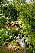 Versteckter Platz mit Blech Giesskannen und Tisch mit Pflanzengefässen im Garten