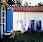 Weiß-blaue Liegestühle an weisser Holzwand