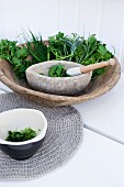 Fresh kitchen herbs with a stone mortar in a rustic wooden bowl
