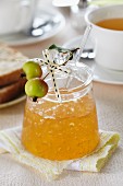 A jar of apple jelly on a breakfast table decorated with ornamental apples