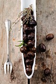 Schwarze Oliven aus Nyons, Frankreich, mit Thymian und Rosmarin