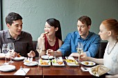Four friends eating food in restaurant