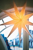 Illuminated paper star lamp in front of arched window