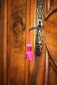 Key with pink tassel in antique wooden door