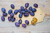 Fresh plums on a chopping board and on a wooden surface