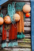 Nets and fishing buoys hanging on weathered wooden wall