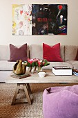 Modernes Gemälde in Wohnzimmer mit Textilien aus Naturmaterialien und einfachem Holzcouchtisch