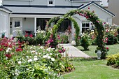 Prachtvoll blühender Garten mit Blumenrabatten und Rosenbögen