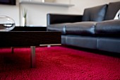 Black leather couch and coffee table with metal legs on red carpet