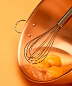 Eggs in a mixing bowl with an egg whisk