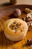 A muffin with nuts on a wooden plate