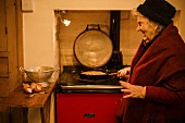 Ältere Frau mit Tortilla in der Pfanne