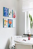Kleine, bunte Gemäldesammlung an weisser Wand in heller Küchenecke