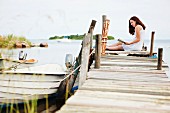 Lesende junge Frau auf einem Holzsteg sitzend