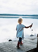 Kleines Mädchen mit Fischernetz auf einem Steg laufend