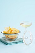 Potato crisps in a glass bowl served with a glass of champagne