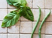 Two String Beans and Fresh Basil on Tile