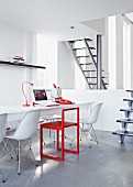 Office in white and red with long desk and white Eames chairs below gallery