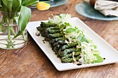 A Platter of Asparagus topped with Grated Cheese, Greens and Balsamic Vinegar