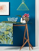 Still-life arrangement on jungle-patterned runner on glass table against blue wall