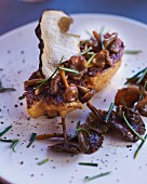 A fried slice of goose liver with mushrooms and chives