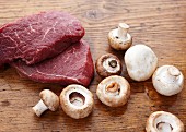 Raw Steak with Raw Mushrooms on a Wooden Surface