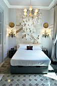 Klassischer Schlafraum mit grossformatigem Blütenbild und schmiedeeisernen Lampen hinter Doppelbett