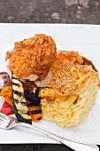 Fried Chicken with Grilled Vegetables and Baked Macaroni and Cheese on a White Plate