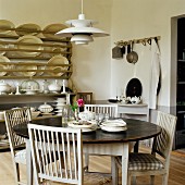 Runder Esstisch mit gepolsterten Küchenstühlen und dänischer 50er Jahre Designer Lampe; Tellerregal im Hintergrund