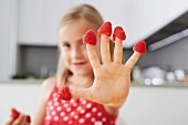 Girl putting raspberries on fingers