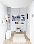 DIY renovations - grey-painted hallway, set of white stools to one side below floating shelf and delicate console table in background below gallery of photos