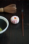 A wagashi chrysanthemum (kiku), a tea whisk, a matcha spoon and matcha tea