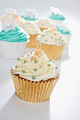 Cupcakes decorated with yellow and green icing and silver balls