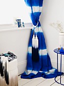Blue and white curtain with tassels in corner of room