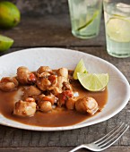 Grilled scallops with sauce and lime wedges